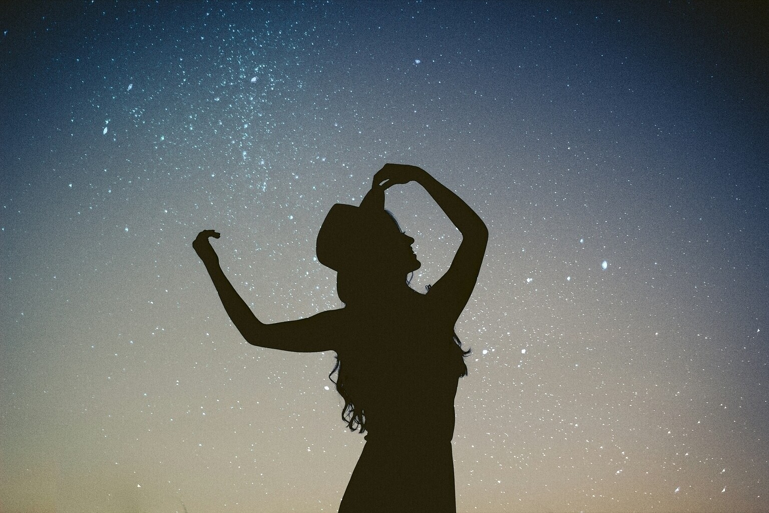 Tanzende Frau als Silhouette vor Sternenhimmel